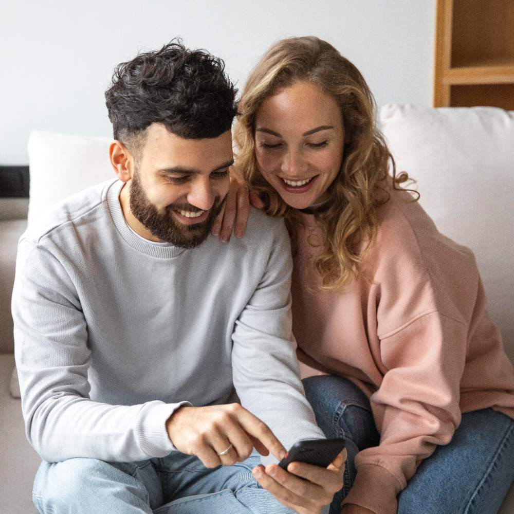 Casal sorridente celebrando um momento romântico com o OurLoveTimer no celular